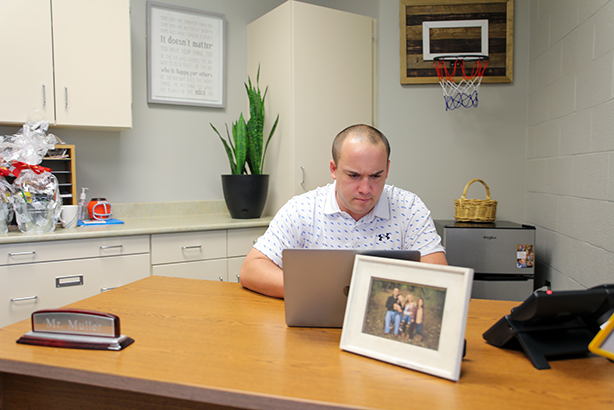 Elementary school principal sitting at a computer in his office