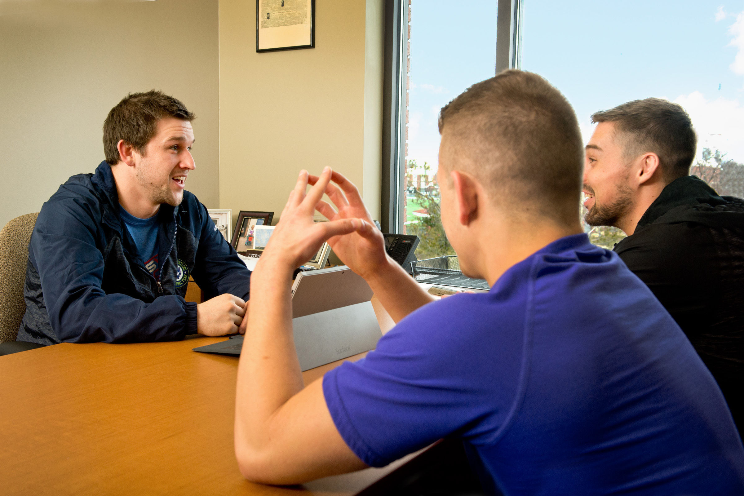 Wrestling coach meeting with athletes in his office.