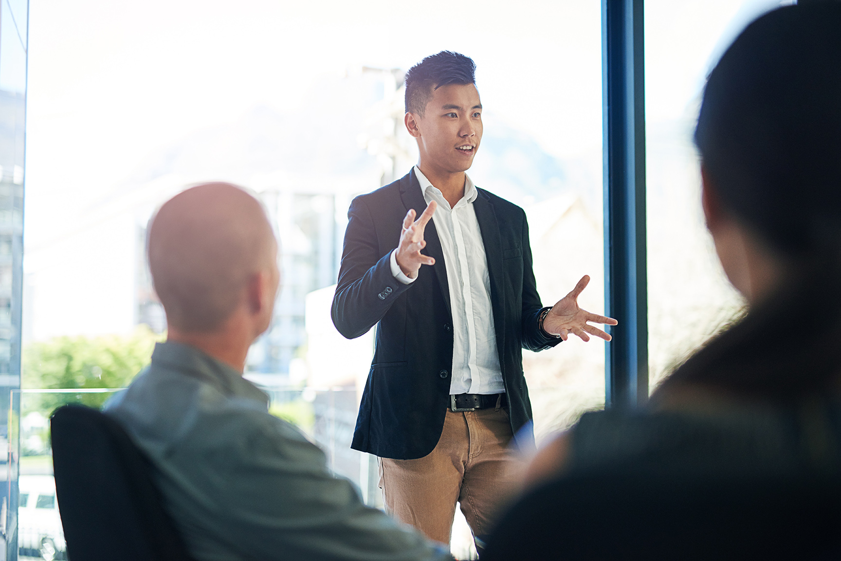 Young business professional speaking in front of business partners.