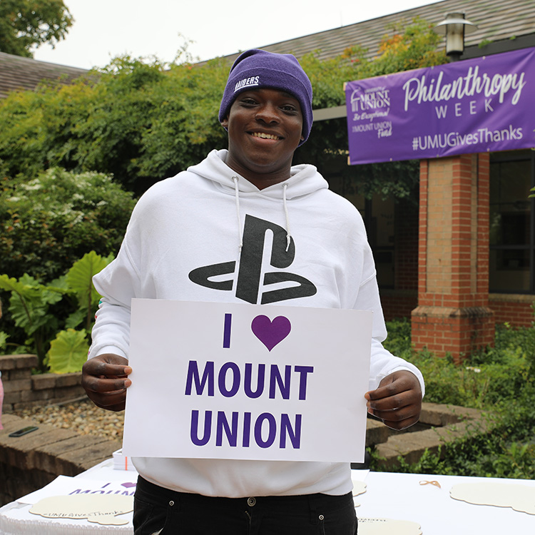 Mount Union student holding "I heart Mount Union" sign on campus.